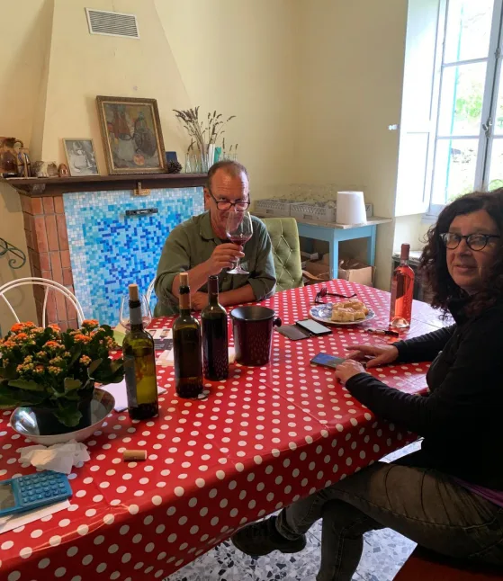 Twee mensen aan een rood-wit tafelkleed met wijn en flessen